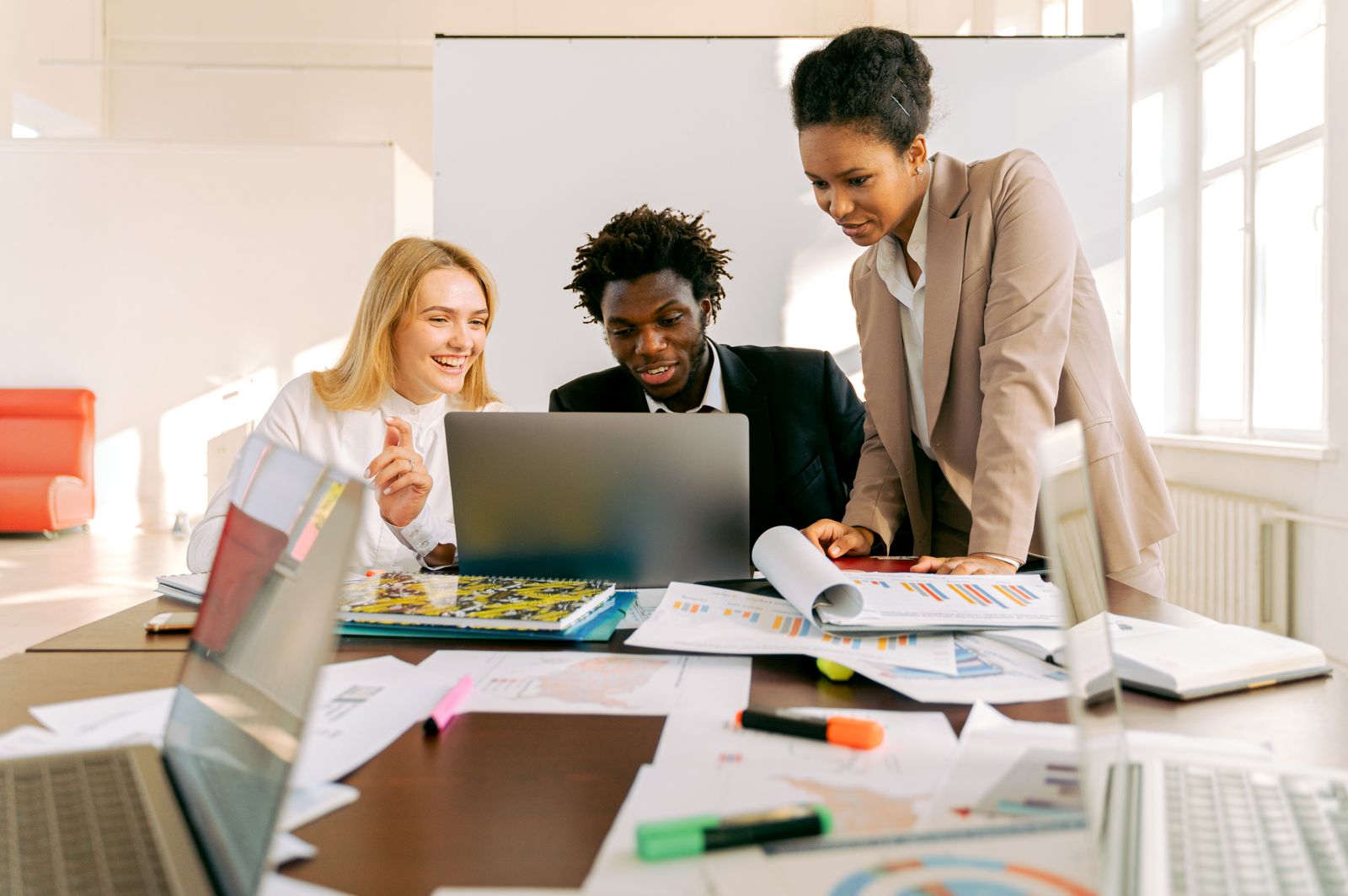 A diverse technology team collaborating around a laptop in a bright modern office